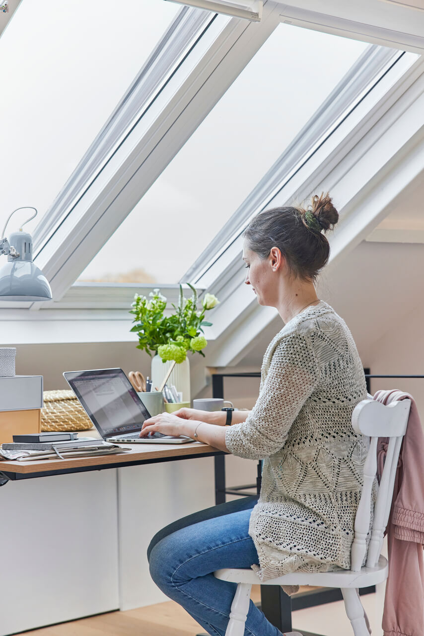 Žena sedí pri stole a pracuje na notebooku